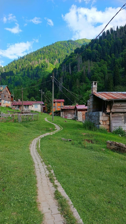 an old road in front of a small town with trees and mountains