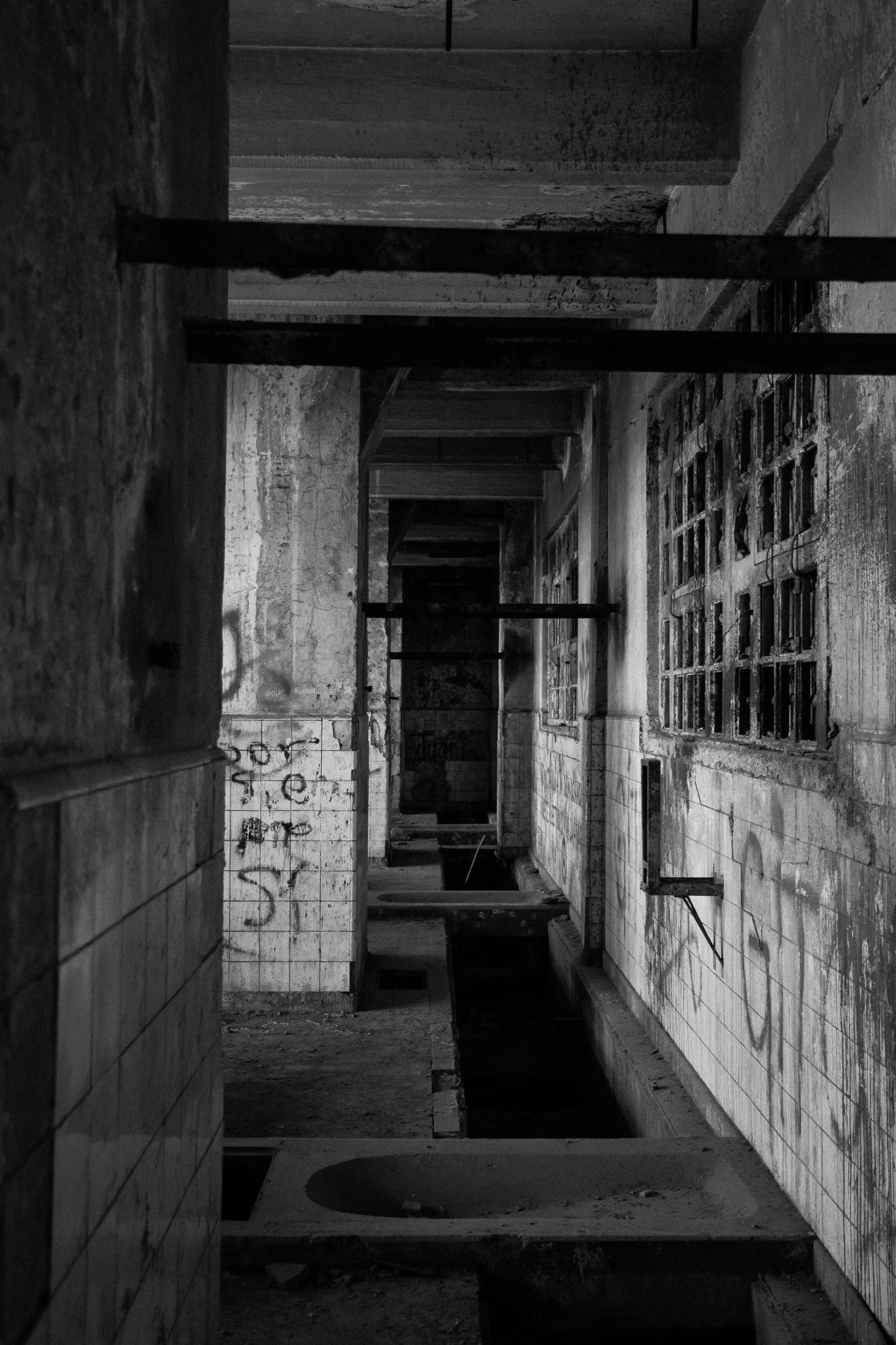 an empty hallway with concrete walls and graffiti