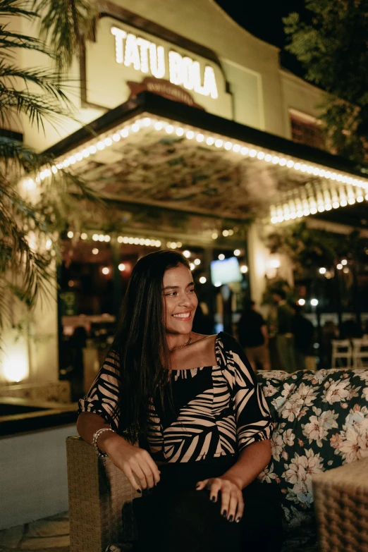 the woman is sitting on the bench near the building