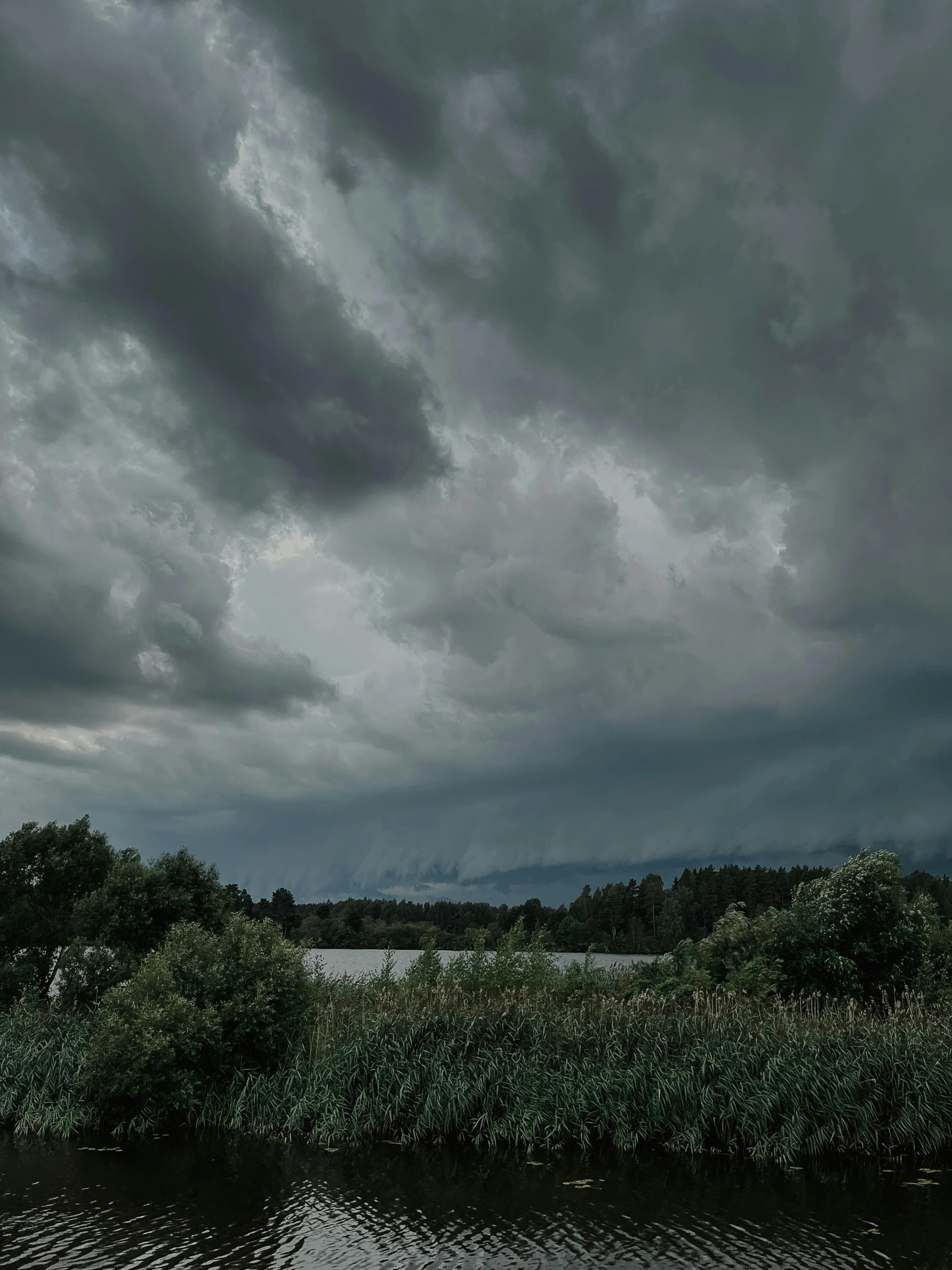 a lake under a dark cloudy sky with boats in the water