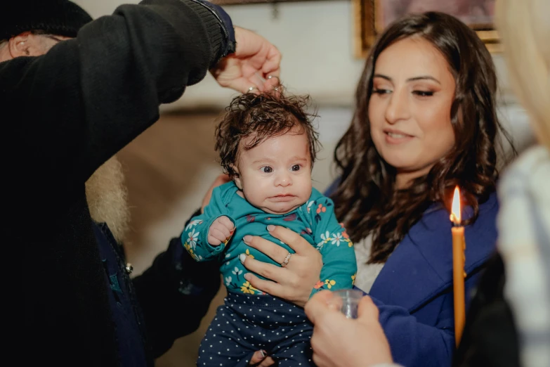 a woman is holding a baby in her arms and a candle on the table