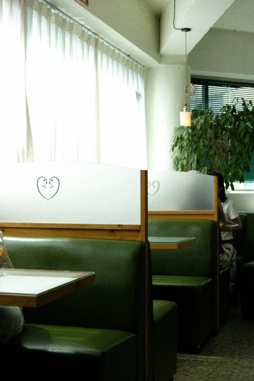 several green booth booths with wood seats, plant and blinds