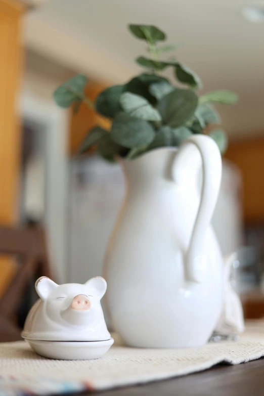 a cute little white bear next to a vase with a plant