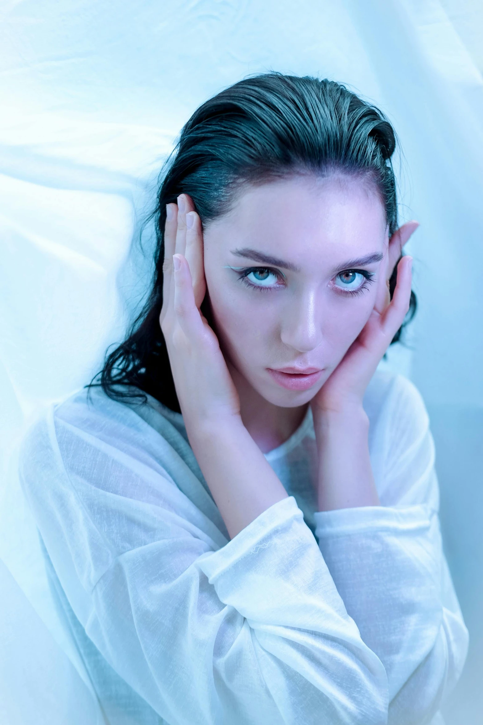 a beautiful woman in white holding her hand to her face