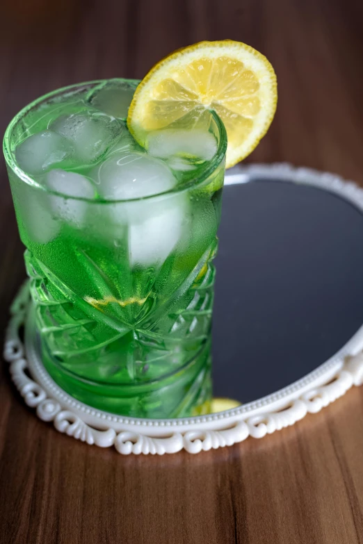 green cocktail with lemon and mint on a wooden table