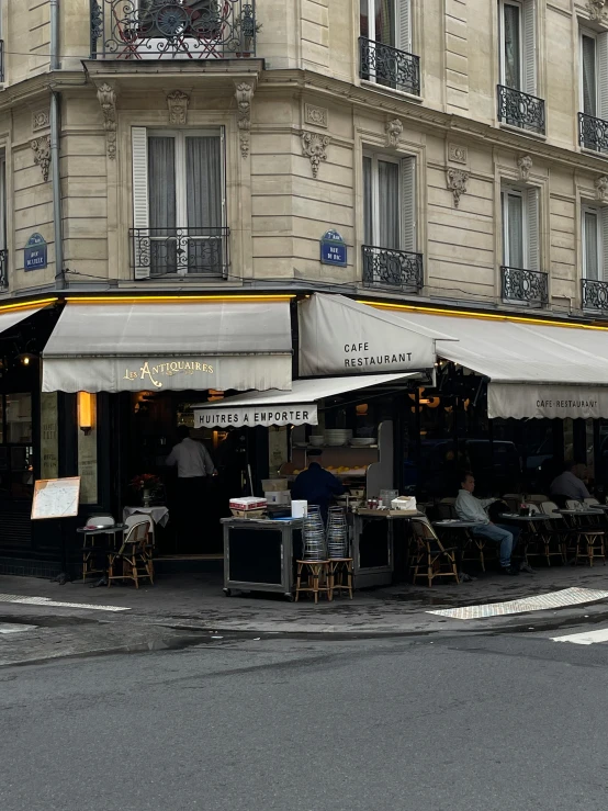 people sitting at tables in the middle of a street