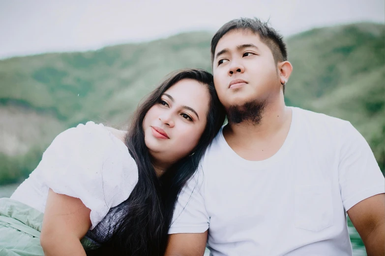 a man sitting next to a young woman in the grass