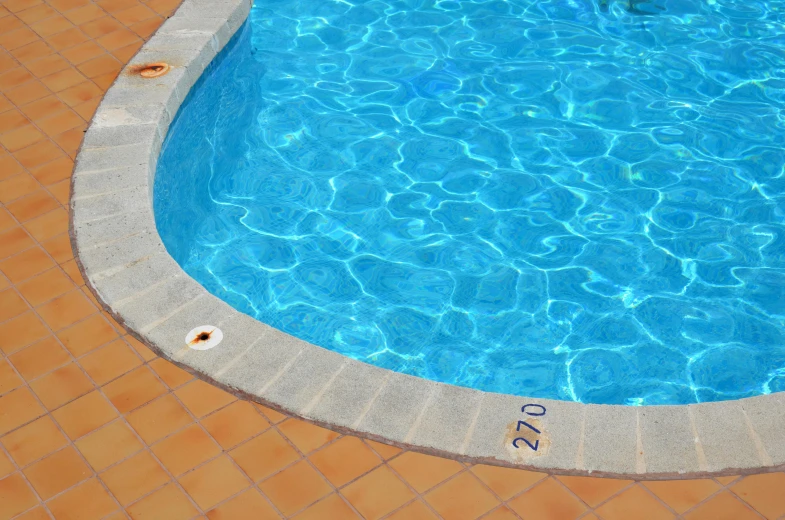 a blue swimming pool with brown and red tiled floors