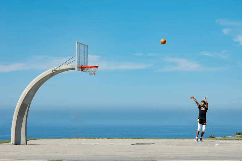 a person throwing a ball into the air in front of a basketball hoop