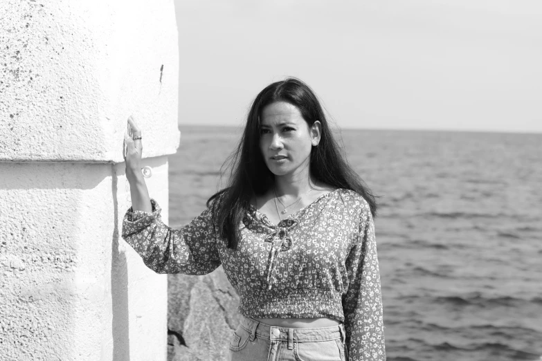 a girl leaning against the sea wall holding a rock