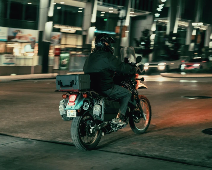 a man on a motorbike in the city at night