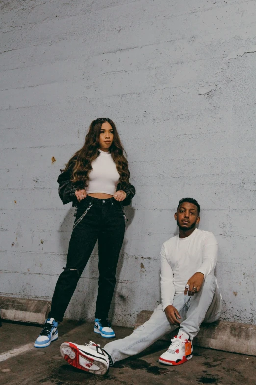 a woman and man are posed together in front of a wall