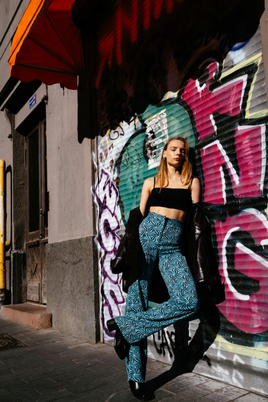 the young woman stands near graffiti covered buildings