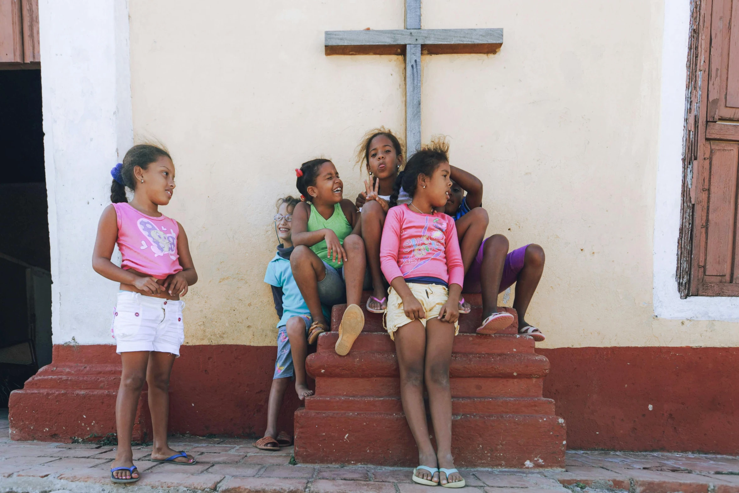 five s sit on stairs at the foot of a cross