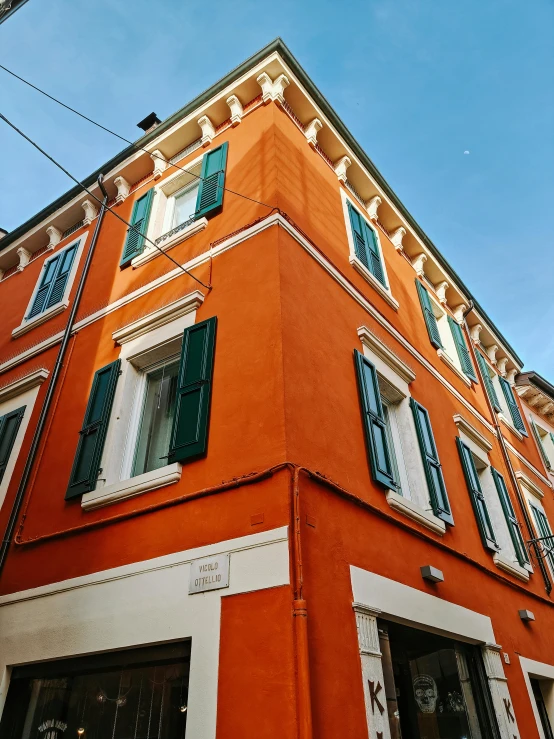 an orange building with shutters on top and the window shutters open