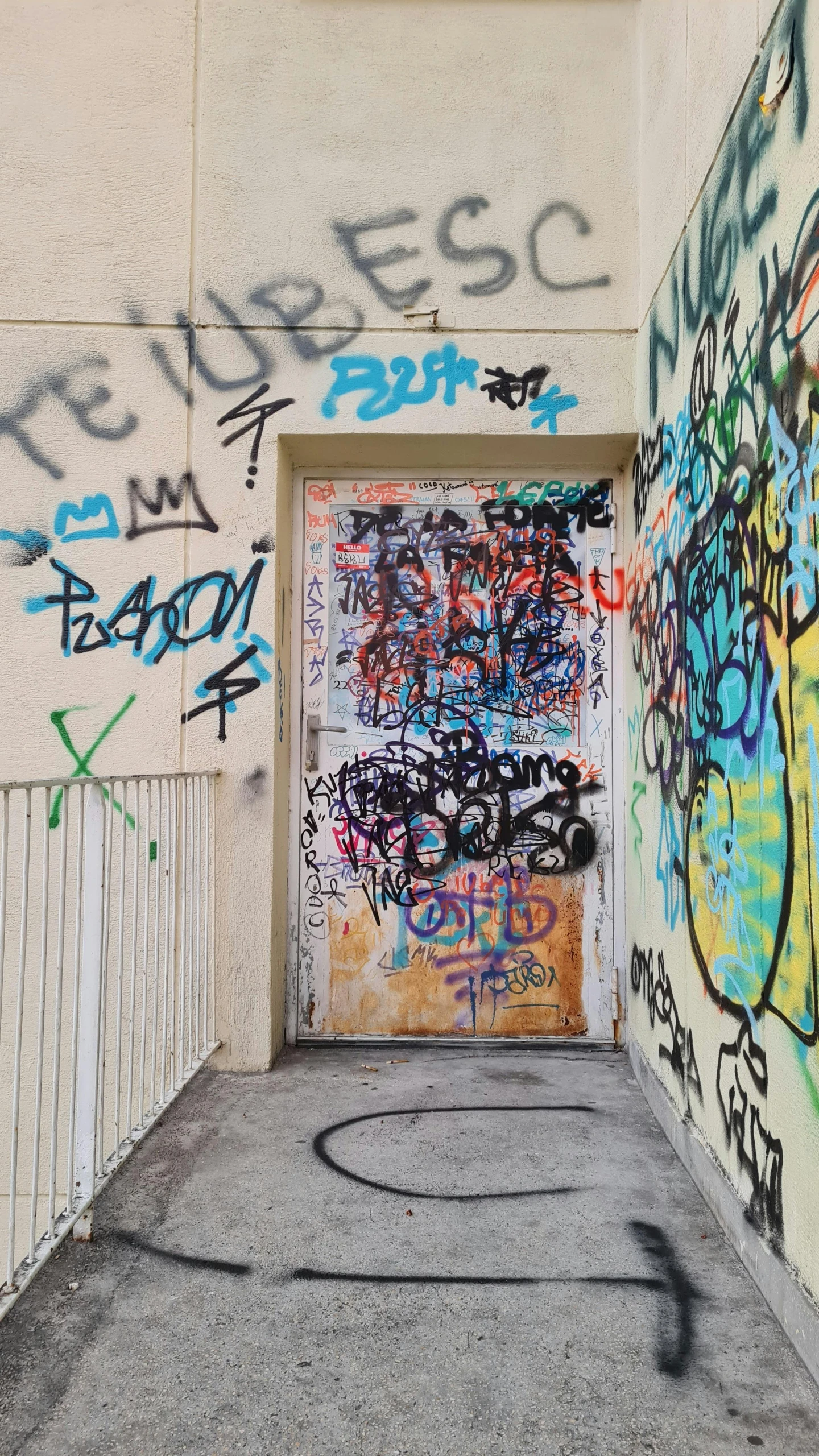 an entrance to a long white building covered in graffiti