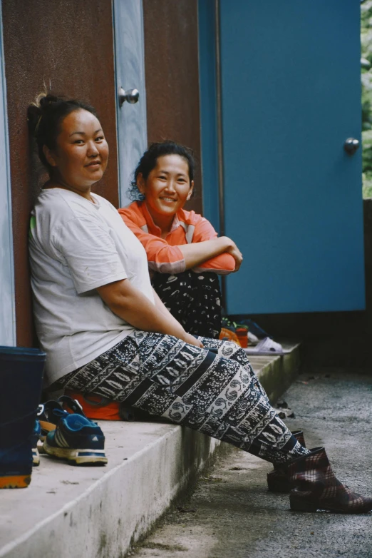 two people sitting and smiling while outside a building