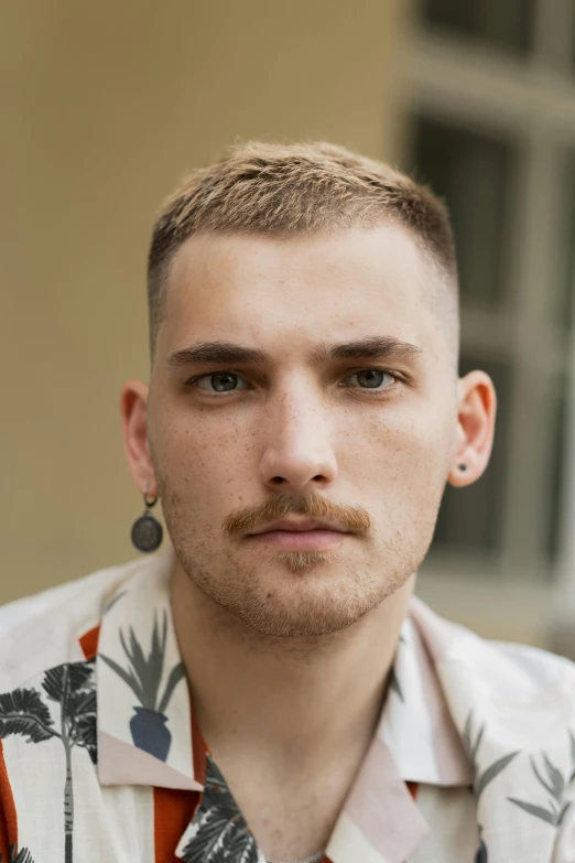 a man wearing an orange and black shirt and silver earrings