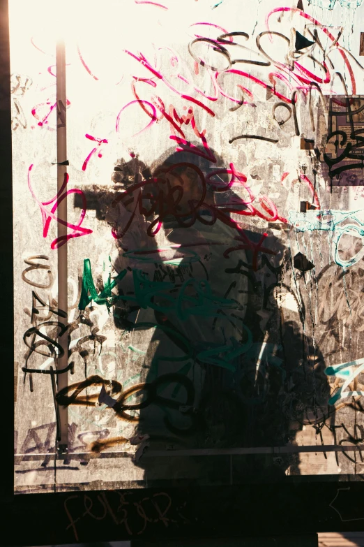 man taking pograph through his reflection in an area covered with graffiti