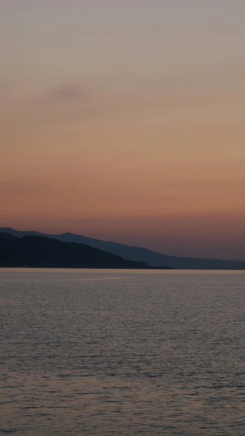 an airplane is flying over the water at dusk