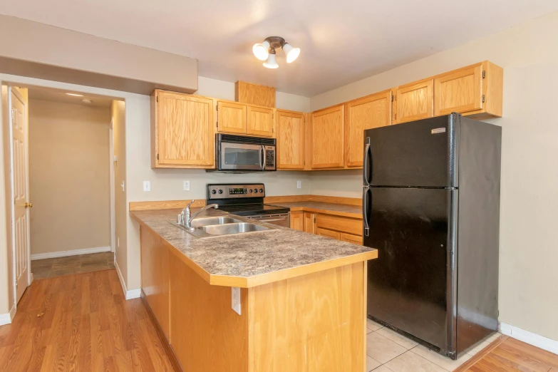 there is a kitchen that has a stainless steel refrigerator and a black refrigerator