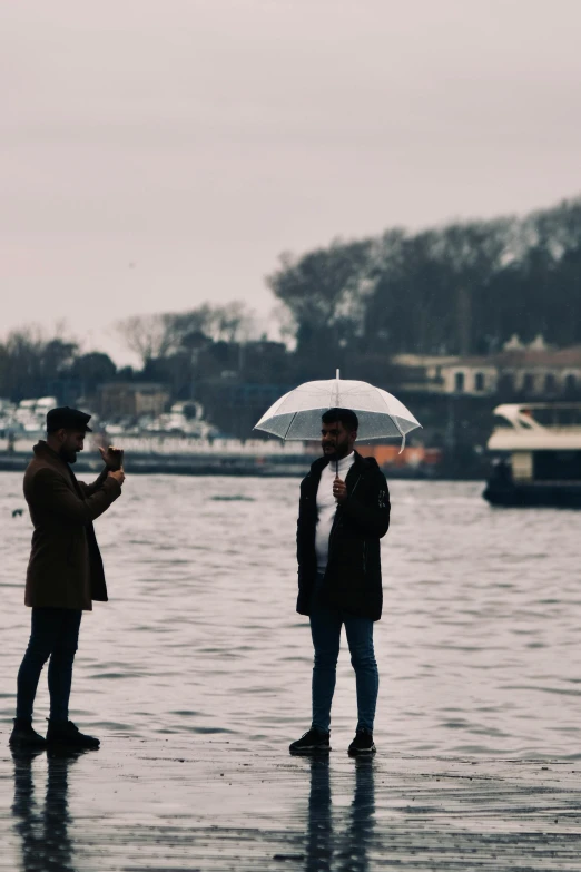 two people are standing in the water with an umbrella
