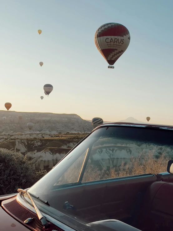 many balloons that are flying above a car