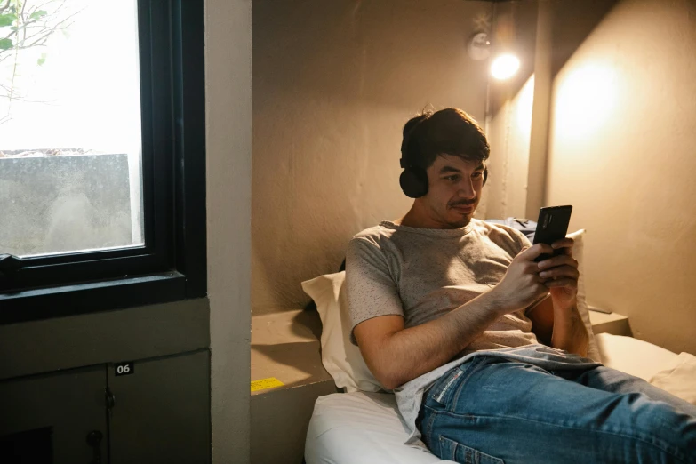 a man sitting on top of a bed in front of a window