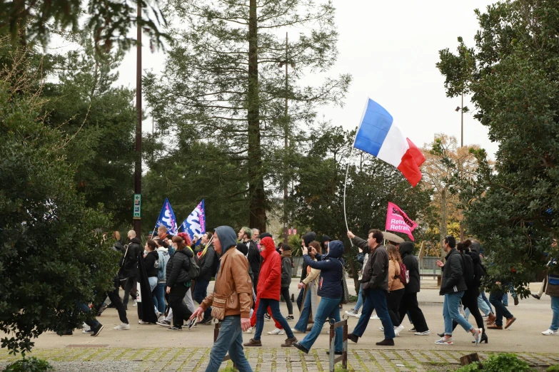 a group of people walk together down a street with flags and trees