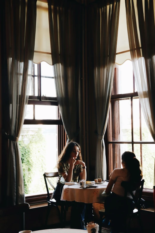 two woman are eating and talking in a restaurant