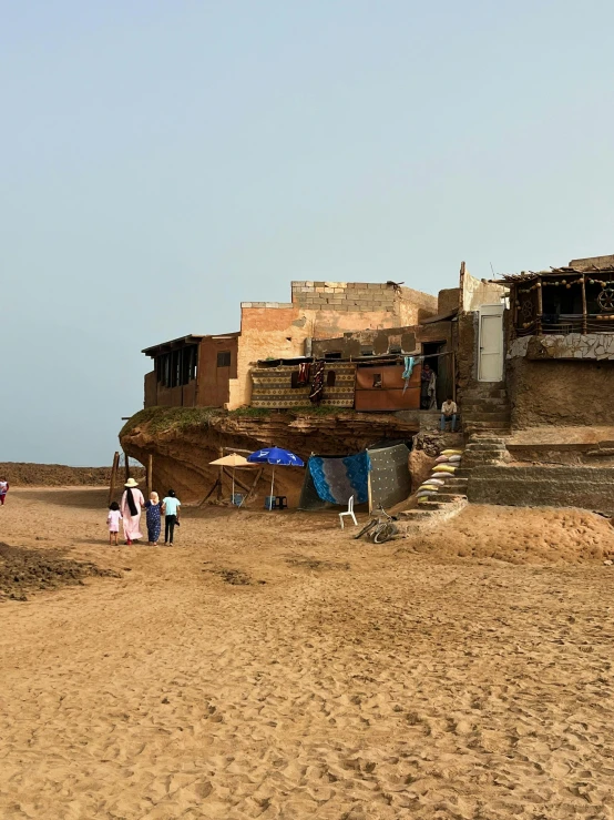 a man with a surfboard walking away from a shack on the beach