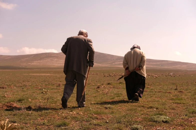 two people walking together with a stick and dog in the grass