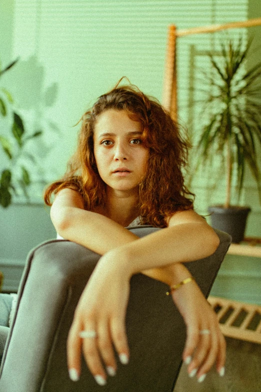 a woman sitting on top of a black chair with her arms crossed