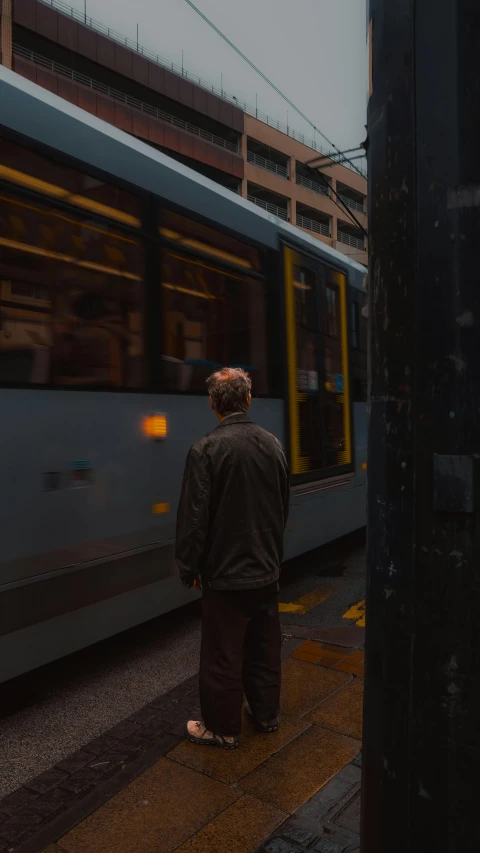 a person waiting for a train on the side of a city street