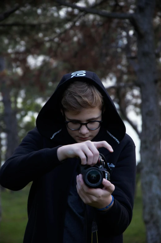 a young man wearing glasses taking a po with a camera