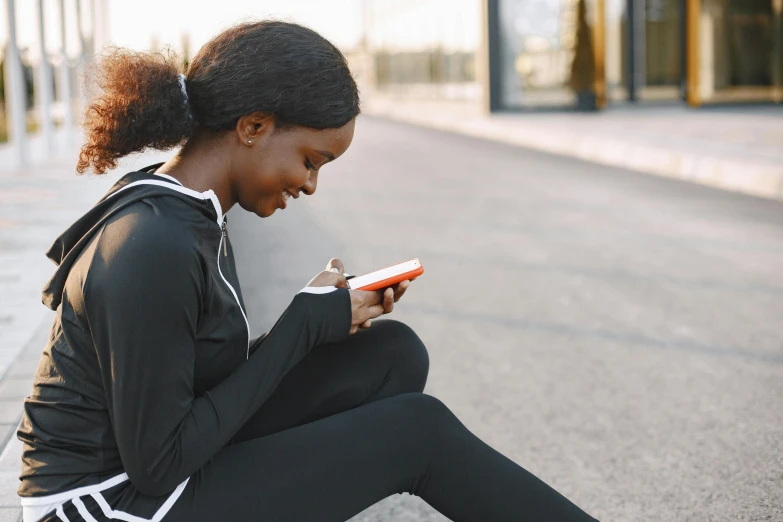 a young woman sitting on the ground checking her phone