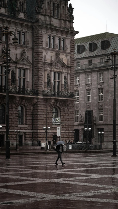 a man crossing an empty city street with a black umbrella