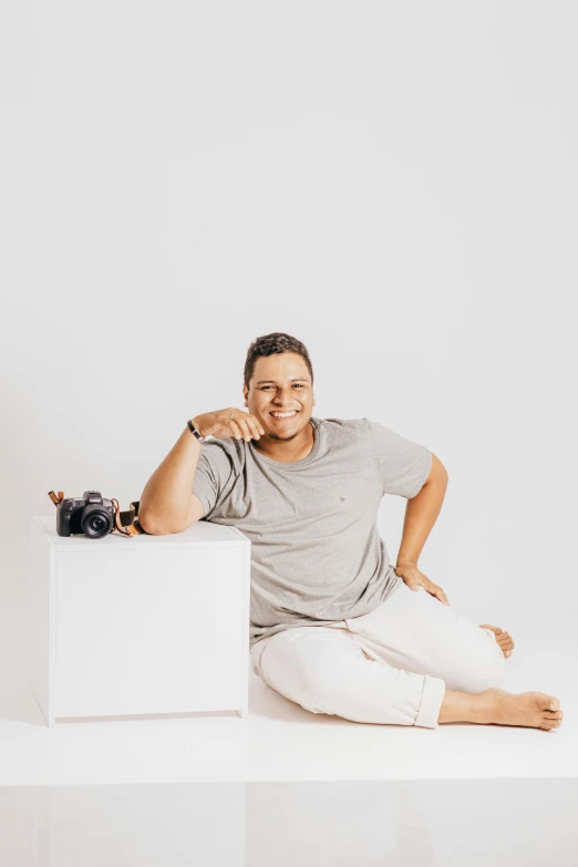 a man in white pants sitting on a white block