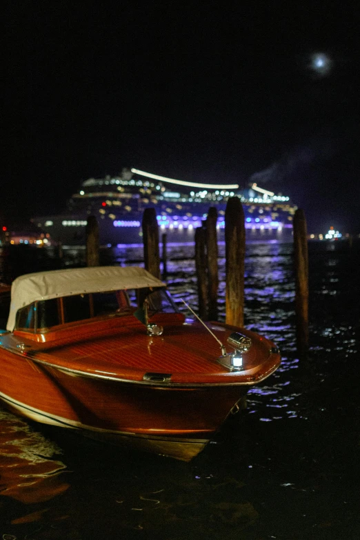 a red speed boat with a cruise ship behind it in a harbor