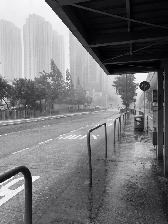 black and white image of sidewalk with sign and rain