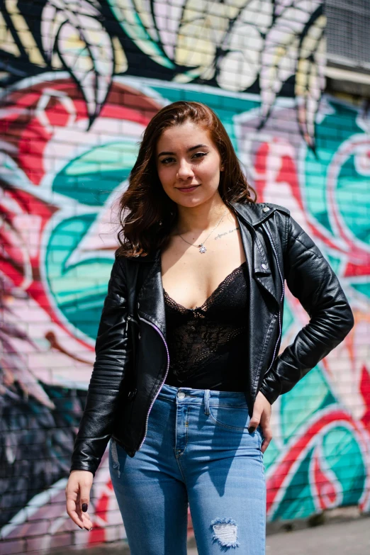 a woman poses for a po in front of a wall with graffiti