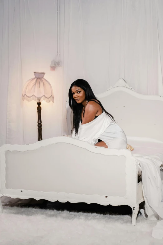 there is a young woman sitting on a white bed