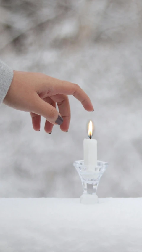 a single lit candle in front of a small glass container with soing in it