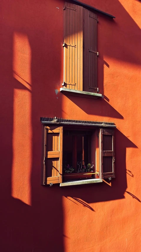 a red building with two open windows and closed shutters