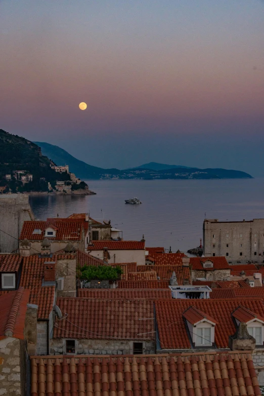 a view of a town at night with a full moon in the sky