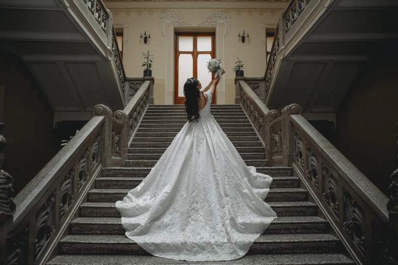 a bride walking down some stairs wearing an ornate wedding gown