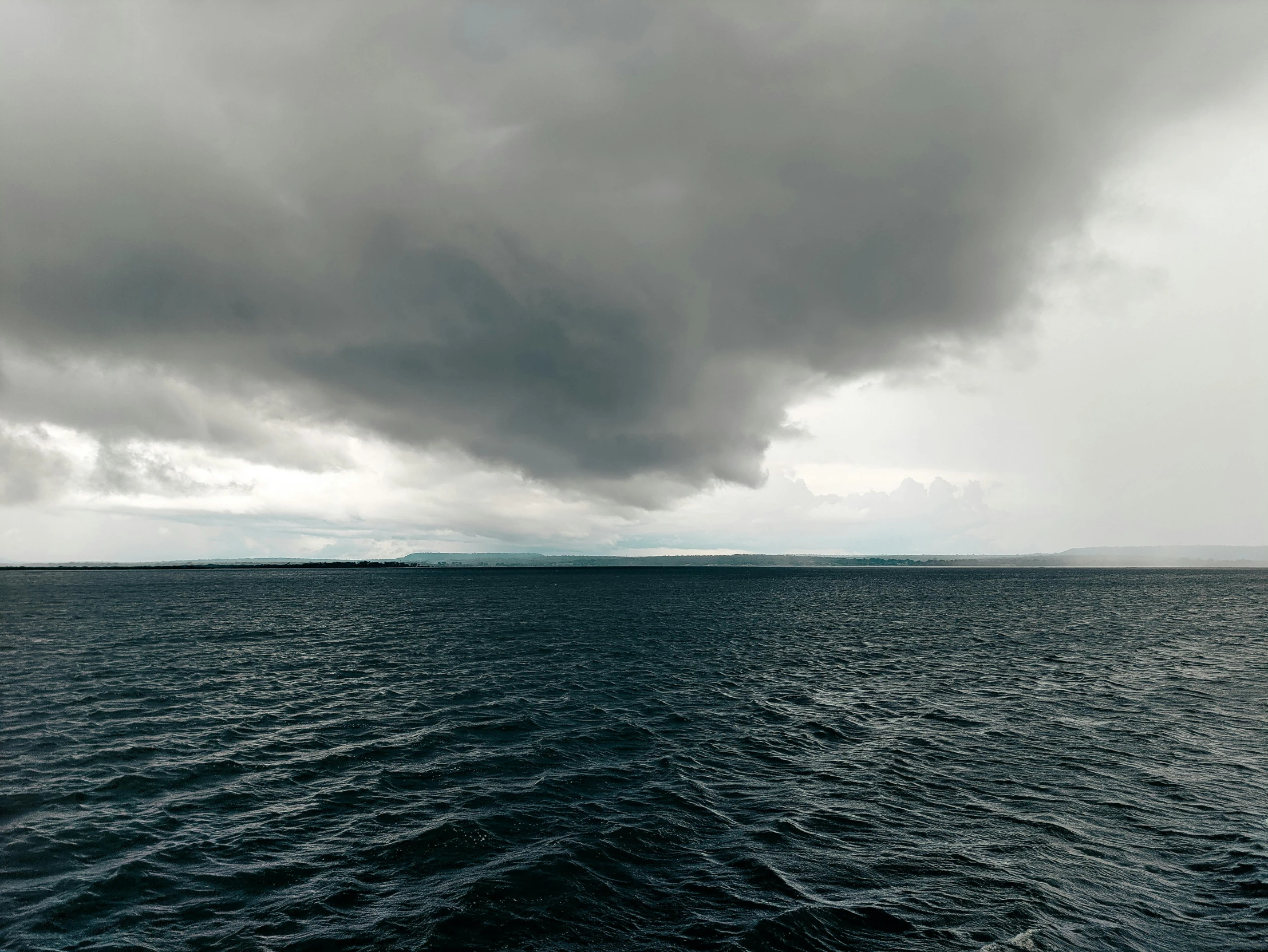 the ocean with dark clouds coming in and it is almost overcast