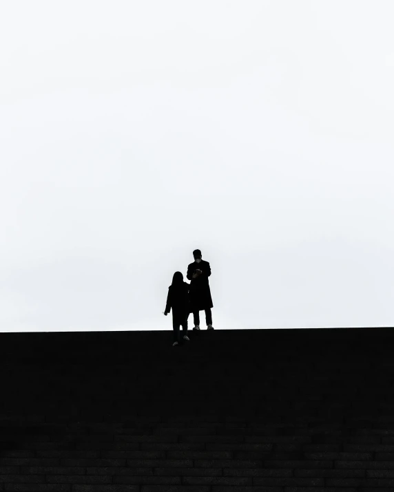 two people on a hill under a cloudy sky