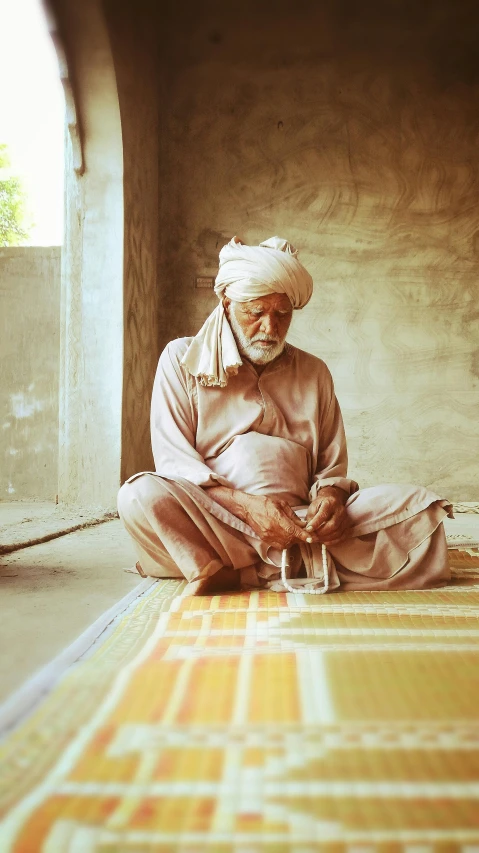 an older man sitting on the ground with a pipe in hand