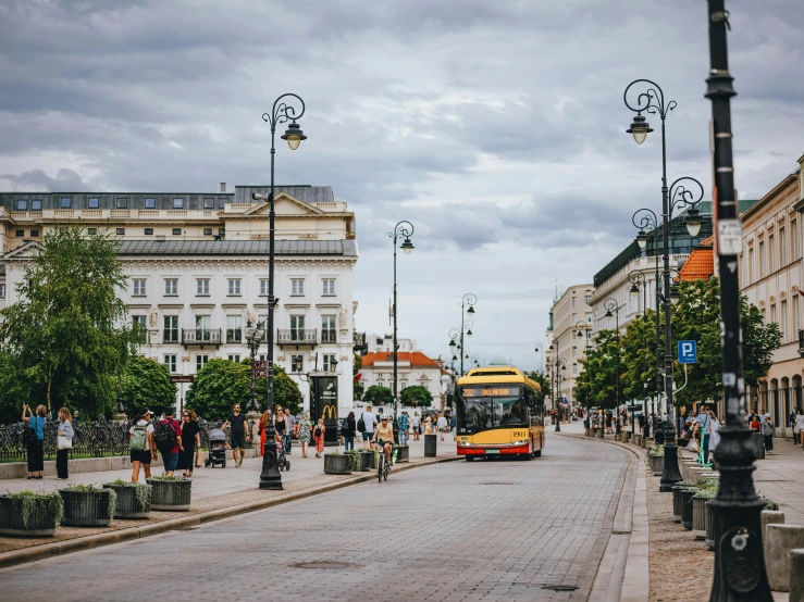 yellow bus driving down a road near people